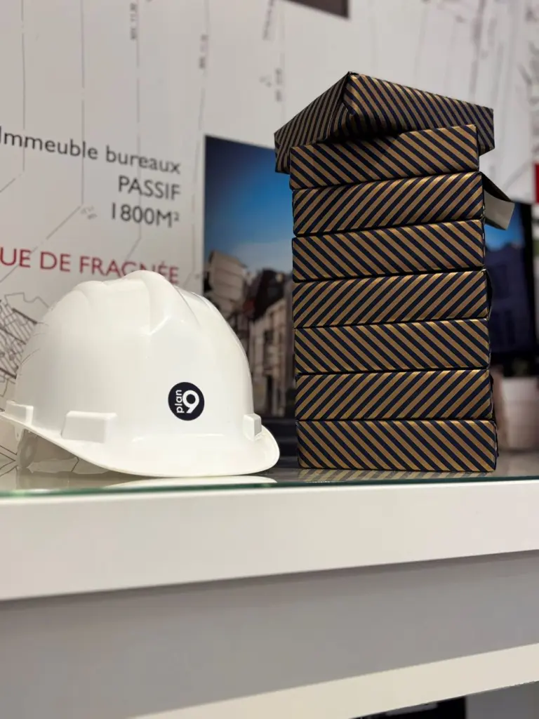 Casque de chantier au logo Plan9 posé sur un bureau